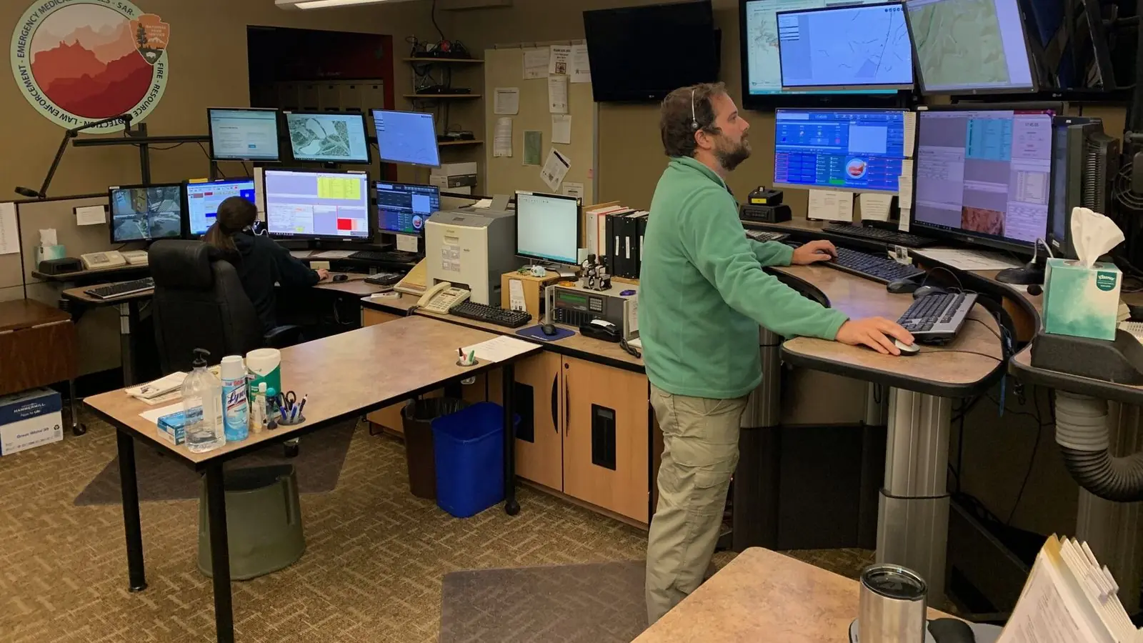 Two dispatchers work at desks lined with monitors and maps at the regional communications center at Grand Canyon National Park, Arizona.