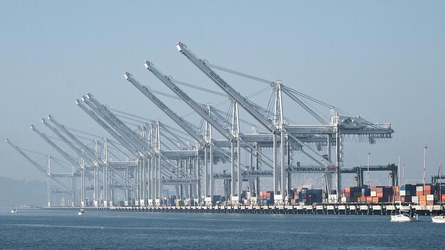 A long row of container cranes lines the waterfront at the Port of Oakland in California.