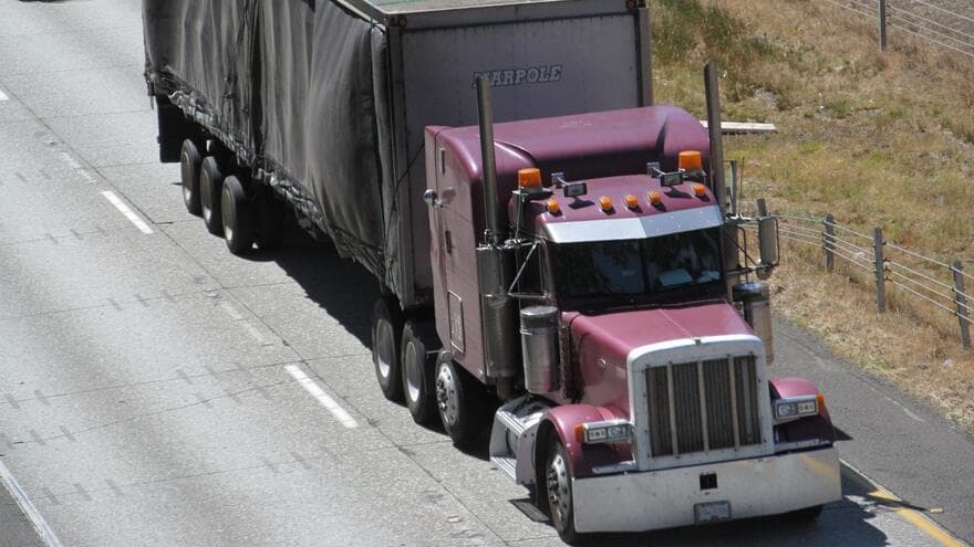 A maroon tractor pulls a tarp-covered semi-trailer along Interstate 5 near Bellingham, Washington.