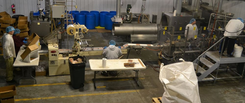 Workers in hairnets run a packaging line on the processing floor of a food company in South Dakota.