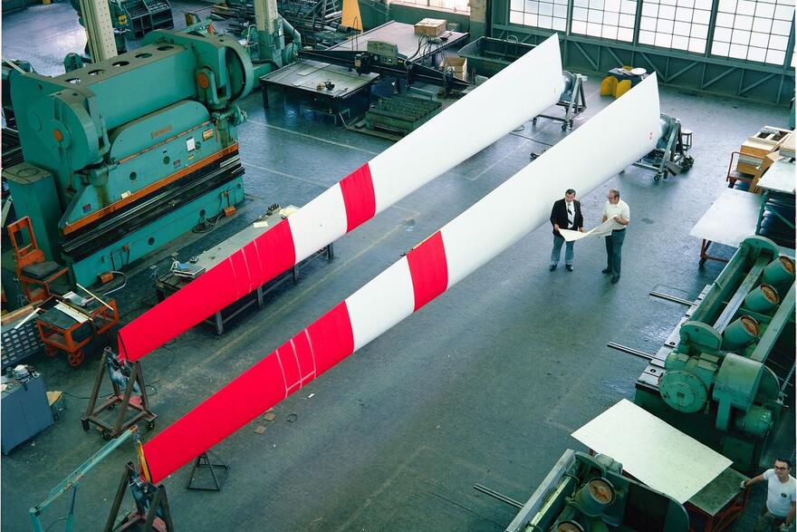 Two men review a drawing on the floor of a metal fabrication shop in Cleveland, Ohio, beside a press brake.